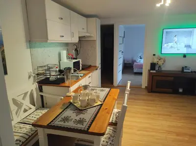 a kitchen with a table and a dining room with a television at Apartament in Rabka