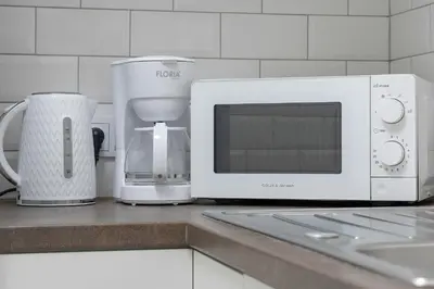 a kitchen counter with a microwave and a coffee maker at Komfortowy Apartament z Klimatyzacją by Noclegi Renters in Kraków