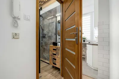 a hallway with a wooden door and a kitchen at Komfortowy Apartament z Klimatyzacją by Noclegi Renters in Kraków