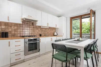 a kitchen with white cabinets and a table and chairs at Old Town Loft - 7 Bedroom Apartment - by Upstairs in Kraków