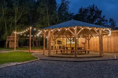 a wooden gazebo with a picnic table and lights at Moon Glamping