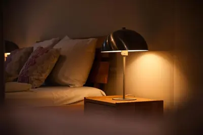 a lamp on a table next to a bed at plac Na Groblach 5 by Homeprime in Kraków