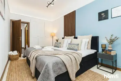 a bedroom with a large bed with blue and white pillows at Smolensk Boutique Stay - homfi Collection in Kraków