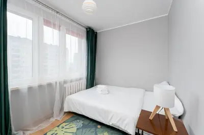 a white bedroom with a bed and a window at Odrzańska Urban Jungle Apartment by BookingHost in Kraków