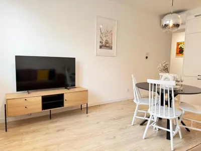 a living room with a tv and a table with chairs at Rakowicka Krakow City Center Premium Apartment with Balcony near Main Station in Kraków
