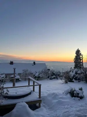 a bench covered in snow with the sunset in the background at Domek na szlaku 70 in Skomielna Biała
