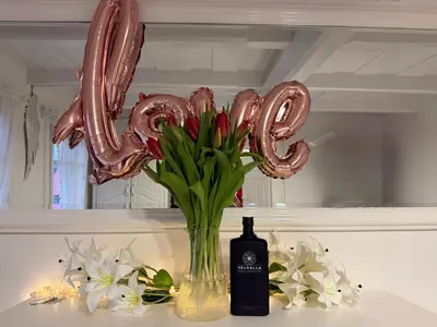 a bottle of wine and a vase of flowers and a balloon spelling love at Domek na szlaku 70 in Skomielna Biała