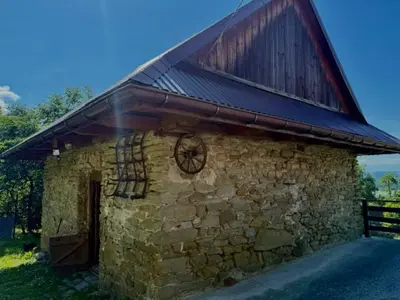 a stone building with a roof with a clock on it at Domek na szlaku 70 in Skomielna Biała