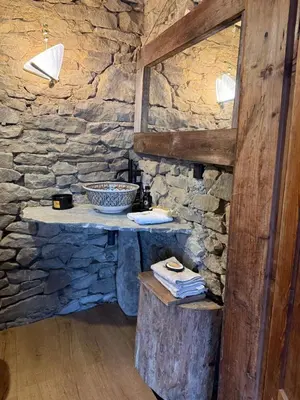 a stone bathroom with a stone wall and a table at Domek na szlaku 70 in Skomielna Biała