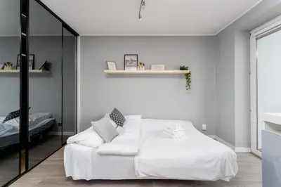 a white bedroom with a white bed and a mirror at Podgórze Pleasant Apartment by BookingHost in Kraków