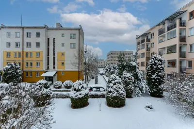 a courtyard covered in snow with buildings and trees at Podgórze Pleasant Apartment by BookingHost in Kraków
