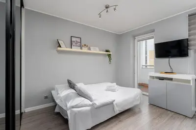 a white living room with a white couch and a tv at Podgórze Pleasant Apartment by BookingHost in Kraków
