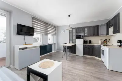 a kitchen with black and white cabinets and a tv at Podgórze Pleasant Apartment by BookingHost in Kraków