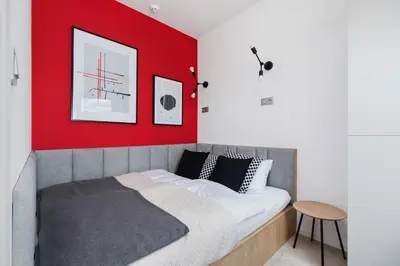 a bedroom with a red accent wall and a bed at Apartamenty EN Zator in Podolsze
