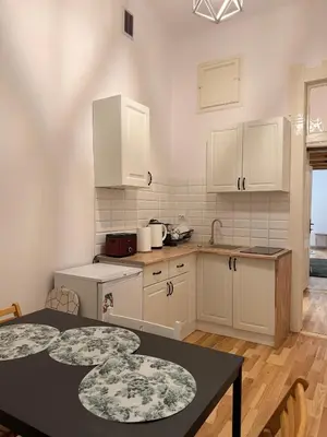 a kitchen with white cabinets and a table at Meiselsa Residence in Kraków