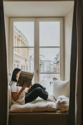 a woman sitting on a window sill reading a book at Bogoria House in Kraków