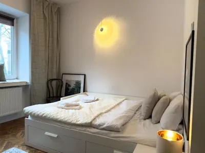 a white bed in a room with a light on the wall at Premium Studio - Free Parking - Near Old Town in Kraków