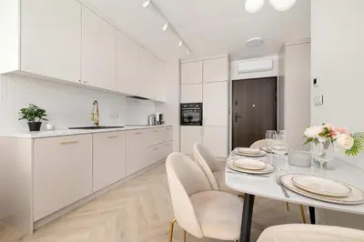 a white kitchen with a table and chairs at Stylowy Klimatyzowany Apartment Blisko Tauron Areny by Noclegi Renters in Kraków