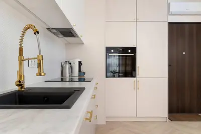 a kitchen with white cabinets and a sink at Stylowy Klimatyzowany Apartment Blisko Tauron Areny by Noclegi Renters in Kraków