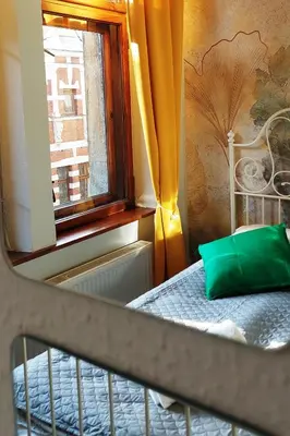 a bedroom with a bed with a window and a green pillow at Cozy Old Town Apartments in Kraków