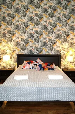 a bedroom with a bed and a wall with a flower pattern at Cozy Old Town Apartments in Kraków