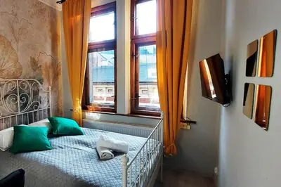a bedroom with a bed with green pillows and a window at Cozy Old Town Apartments in Kraków