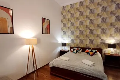 a bedroom with a bed and two lamps and a wall at Cozy Old Town Apartments in Kraków