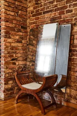 a wooden chair sitting in front of a brick wall at Loft Apartment Industrial Design in Kraków