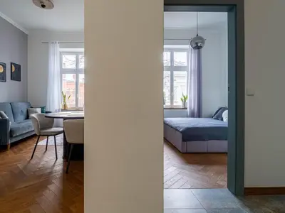 a bedroom and a living room with a bed and a table at Apartament Mostowa in Kraków