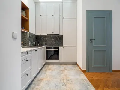 a kitchen with white cabinets and a blue door at Apartament Mostowa in Kraków