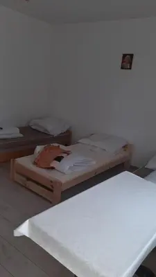 two beds in a room with a white wall at Pokoje do wynajęcia w domku