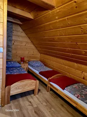 two beds in a log cabin bedroom with wooden walls at Domek pod Babią Górą in Zawoja