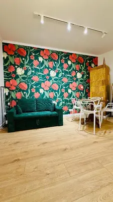 a living room with a green couch and a floral wall at Kraków Old Town Place in Kraków