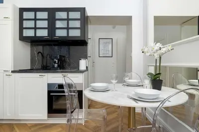 a white kitchen with a table and chairs at Klimatyczne Studio obok Starego Miasta by Noclegi Renters in Kraków