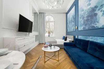 a living room with a blue couch and a tv at Klimatyczne Studio obok Starego Miasta by Noclegi Renters in Kraków