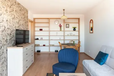 a living room with a tv and a blue chair at Lan Apartament in Kraków