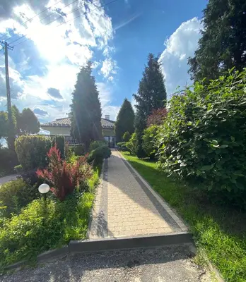 a brick walkway in a yard with bushes and trees at Zajazd Maj in Bolesław