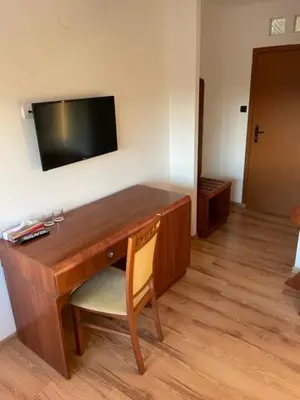 a desk with a television and a chair in a room at Zajazd Maj in Bolesław