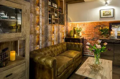 a leather couch in a room with a brick wall at Art & Garden Residence in Kraków