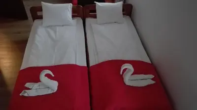 two beds with white and red blanket with swans on them at Willa Julia in Kraków