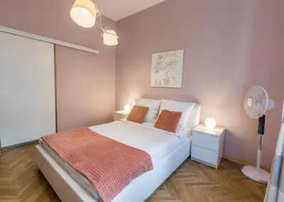 a bedroom with a bed and two lamps and a fan at AR Apartments in Kraków