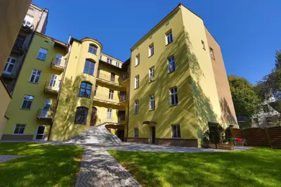 a large yellow building with grass in front of it at AR Apartments in Kraków
