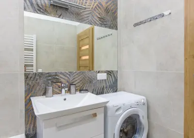 a bathroom with a washing machine and a sink at AR Apartments in Kraków