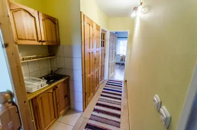 a kitchen with wooden cabinets and a rug on the floor at Agroturystyka Sarenka in Podsarnie