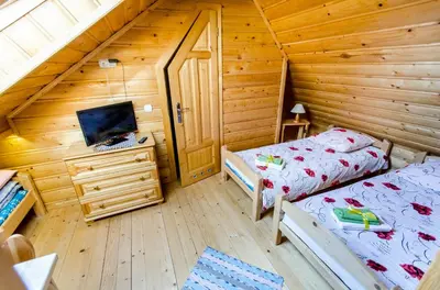 a bedroom with two beds and a desk in a log cabin at Agroturystyka Sarenka in Podsarnie