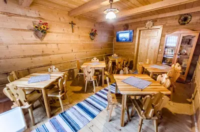an empty restaurant with wooden tables and chairs at Agroturystyka Sarenka in Podsarnie