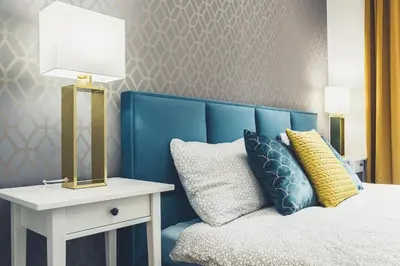 a bed with a blue headboard and a table with a lamp at FatCat Apartments in Kraków