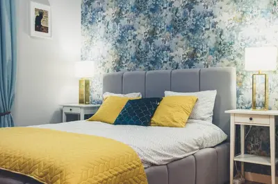 a bedroom with a gray bed with yellow pillows at FatCat Apartments in Kraków