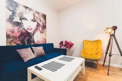 a living room with a blue couch and a painting at FatCat Apartments in Kraków