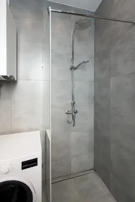 a shower in a bathroom with a washing machine at FatCat Apartments in Kraków